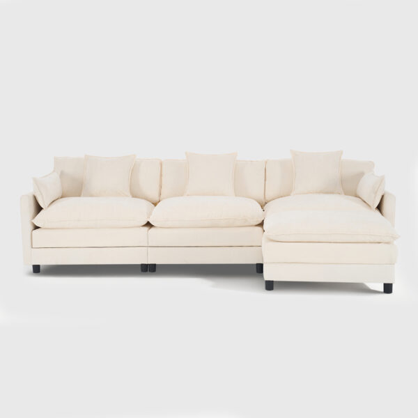 Beige modular sectional sofa with matching ottoman, plush upholstered living room sofa with throw pillows in a bright modern space