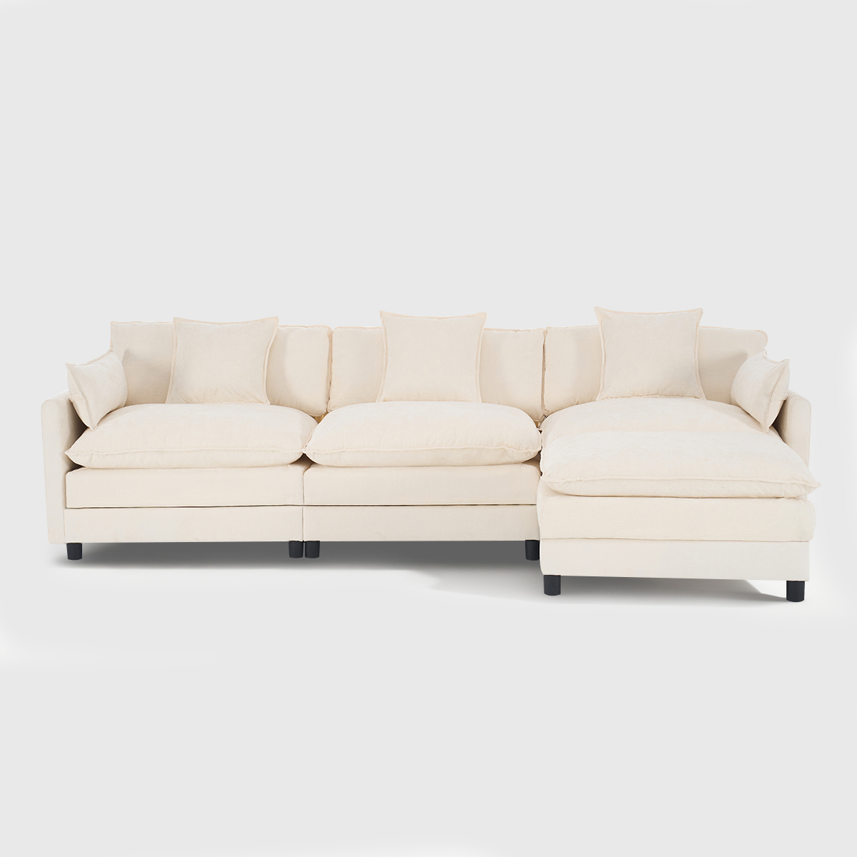 Beige modular sectional sofa with matching ottoman, plush upholstered living room sofa with throw pillows in a bright modern space